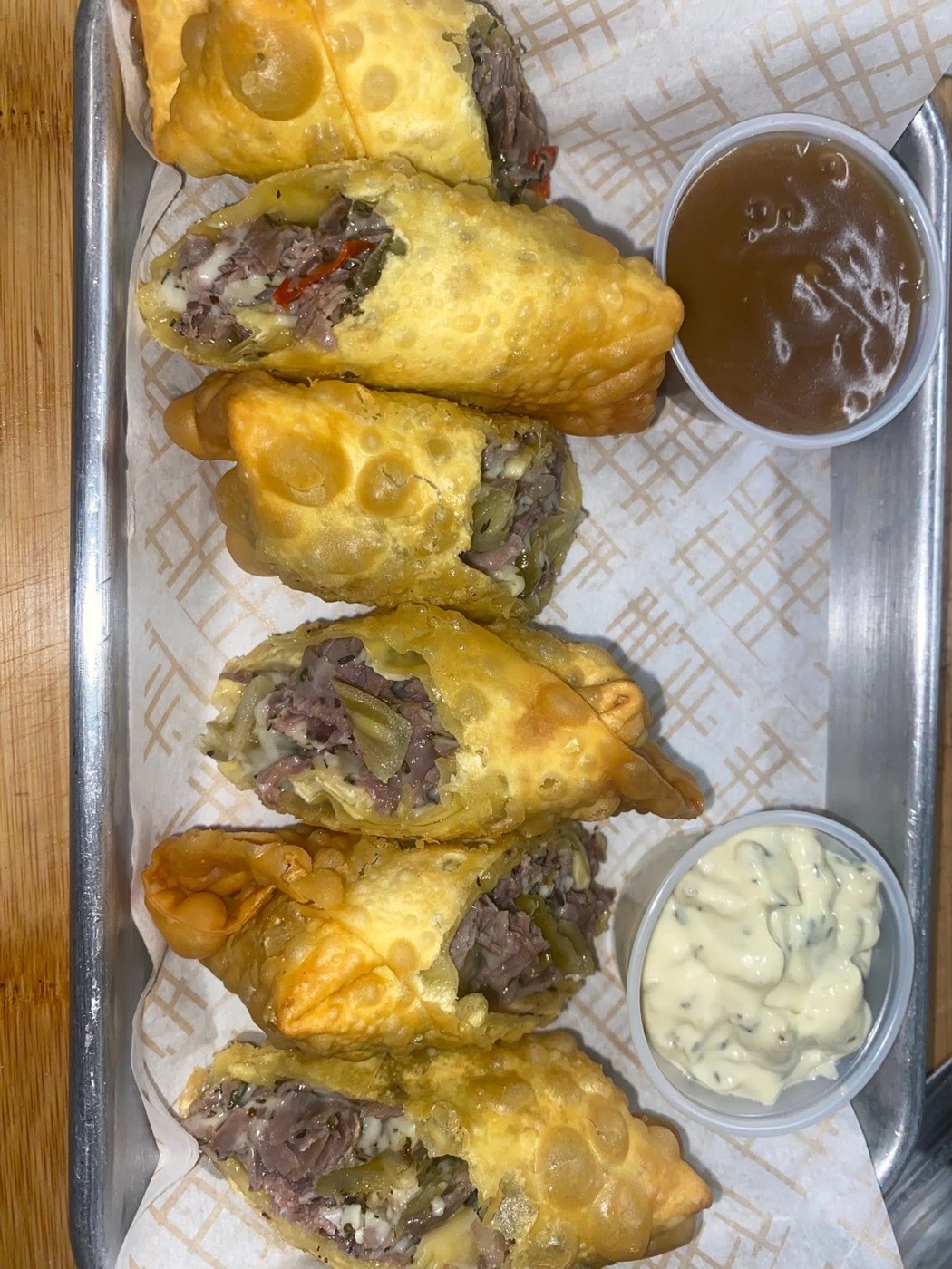 Sliced cheesesteak egg rolls plated with two dipping sauces