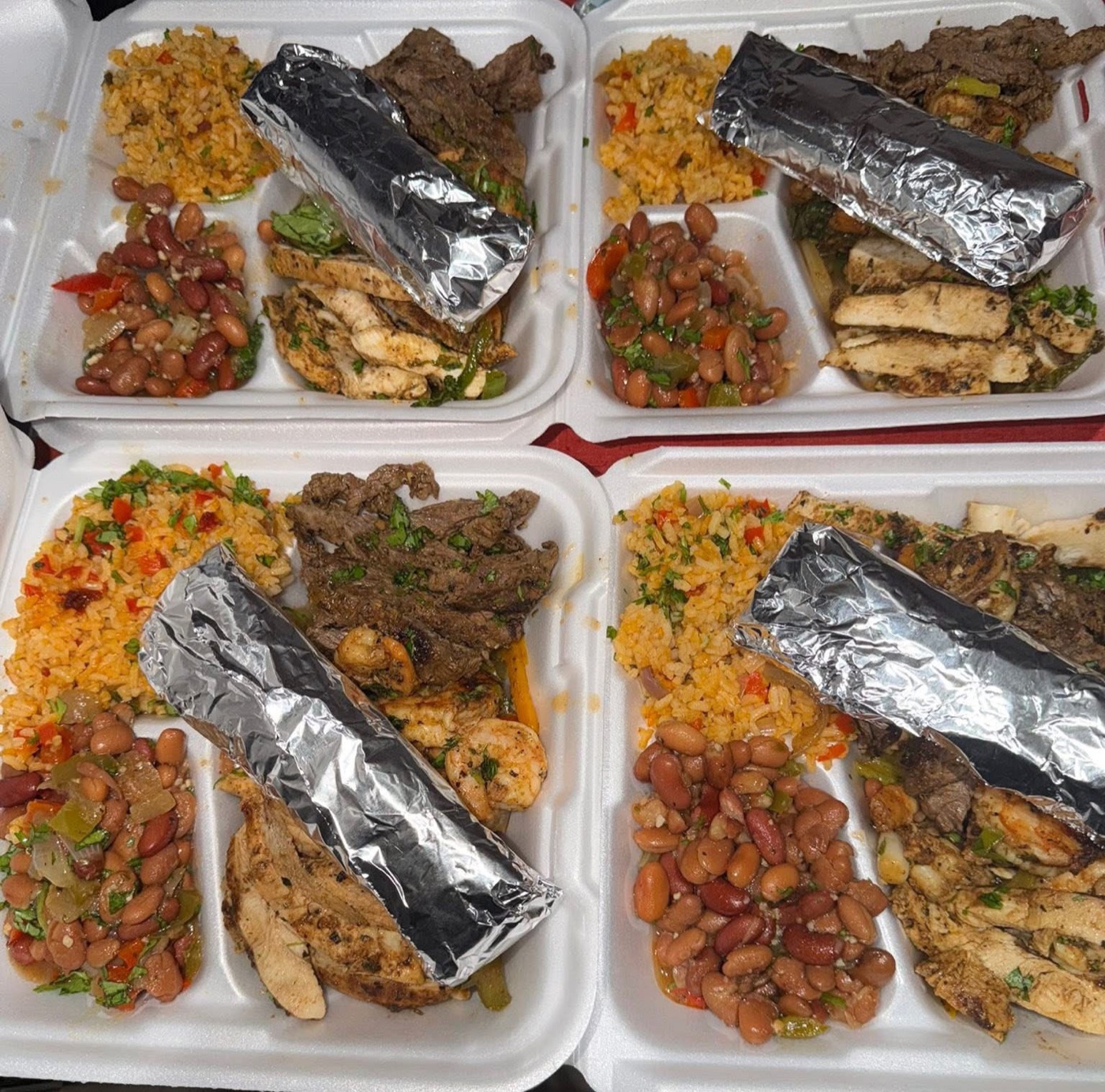 Four fajita plates lined up with rice, beans and garnishes