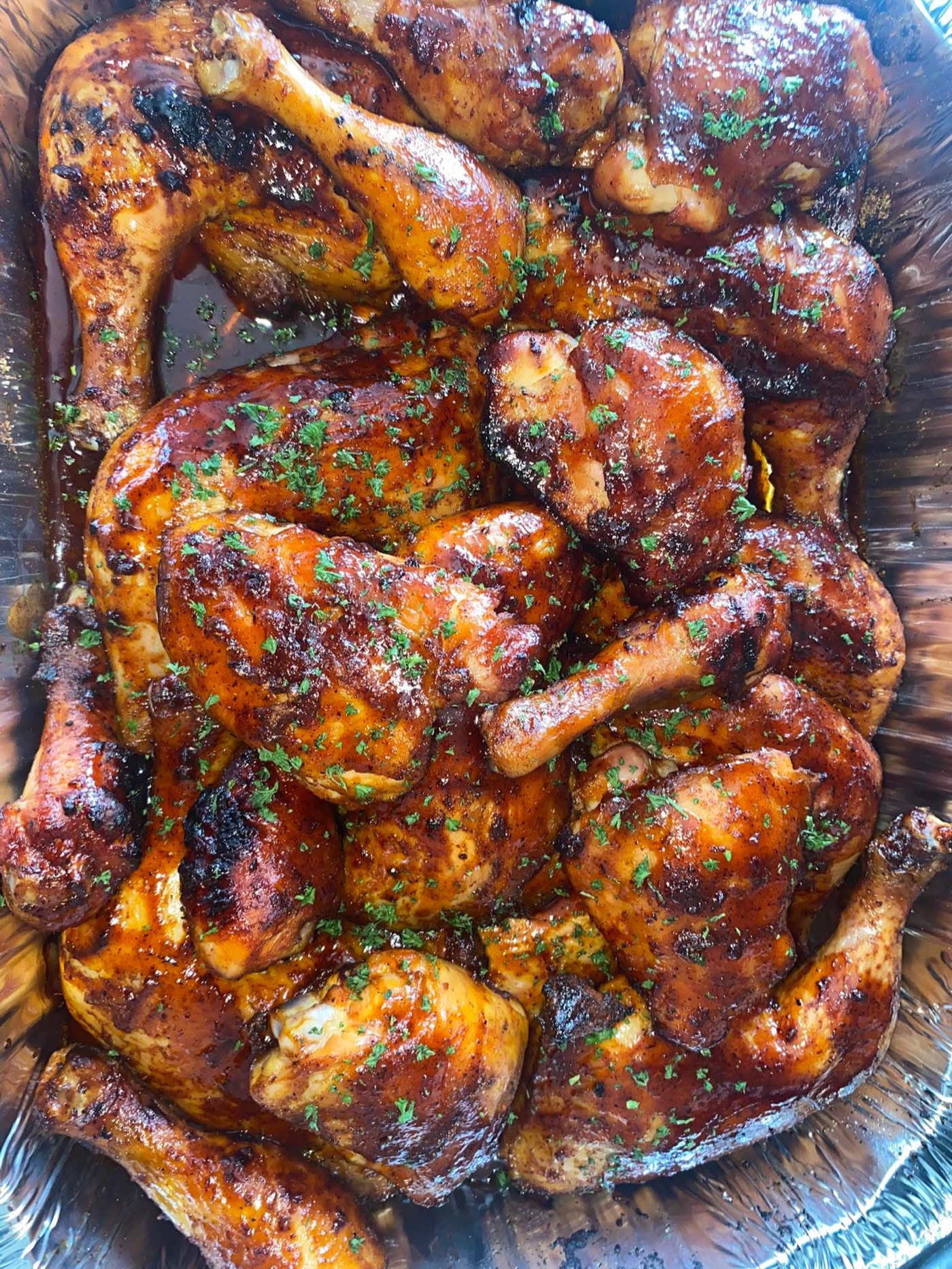 Smoked barbecue chicken quarters resting in a full serving pan