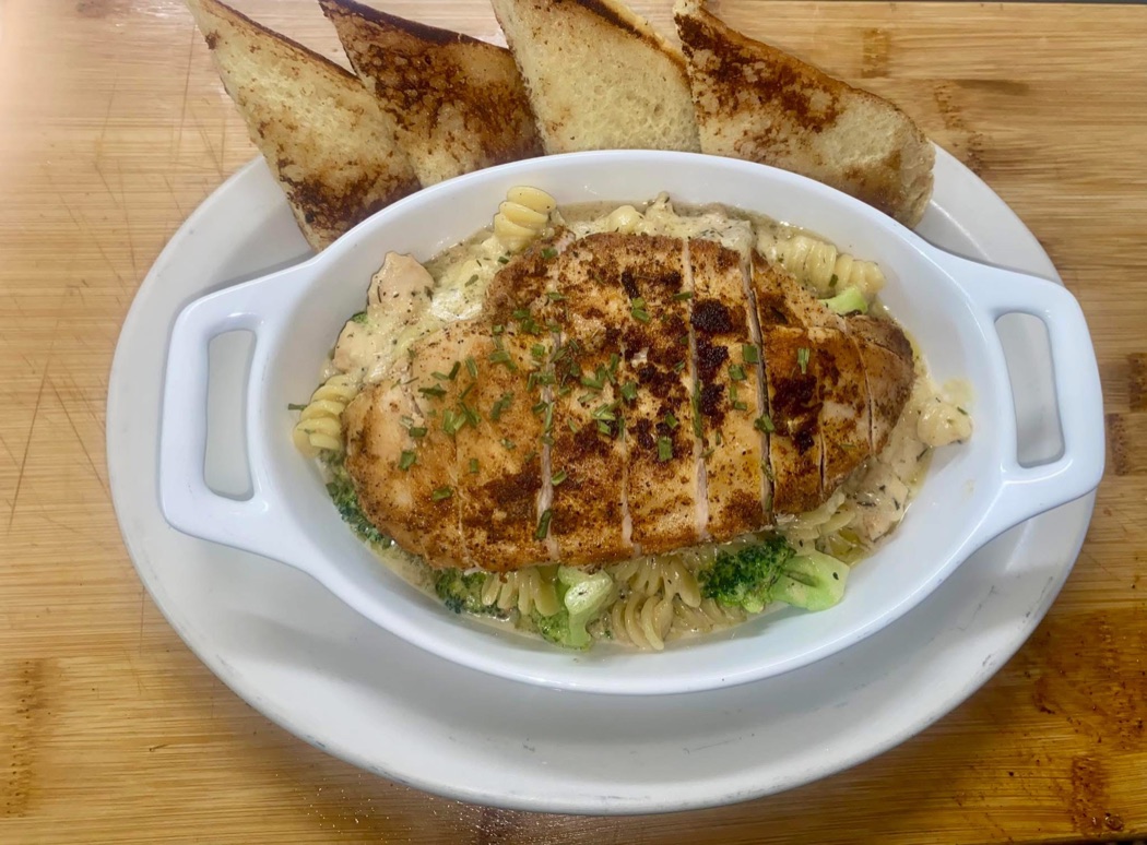 A single plated dish of blackened chicken over cream pasta