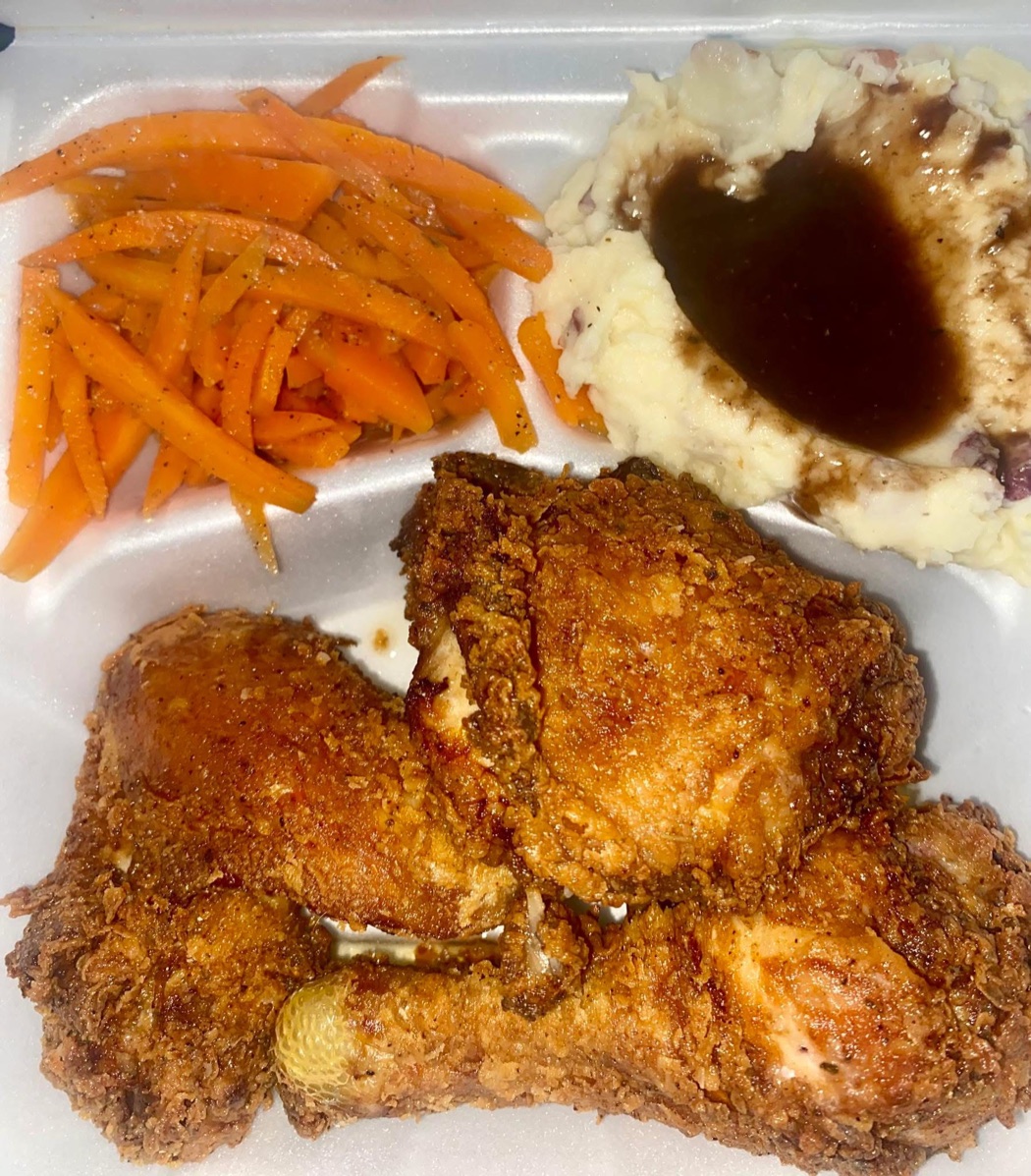 A plate of fried chicken with mashed potatoes and glazed carrots